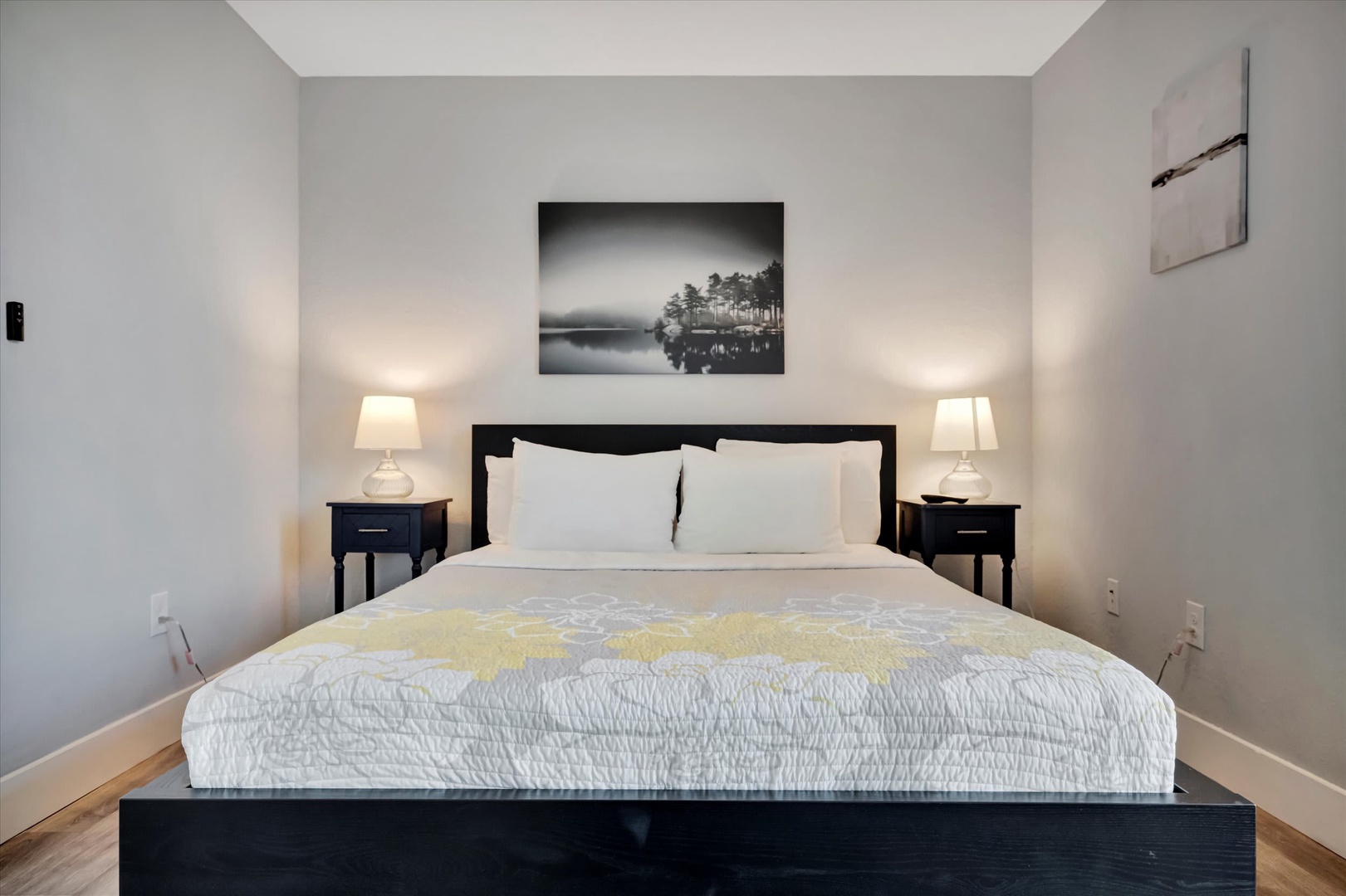 Slip into crisp white linens on your plush bed, flanked by glowing bedside lamps that cast a warm, peaceful ambiance. This serene bedroom invites you to unwind after a day of exploring.