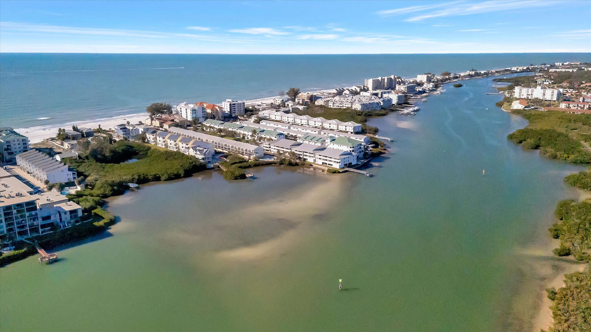 Aerial view of the beachfront community, showcasing the coastal barrier island location between the Gulf and bay with direct beach access.