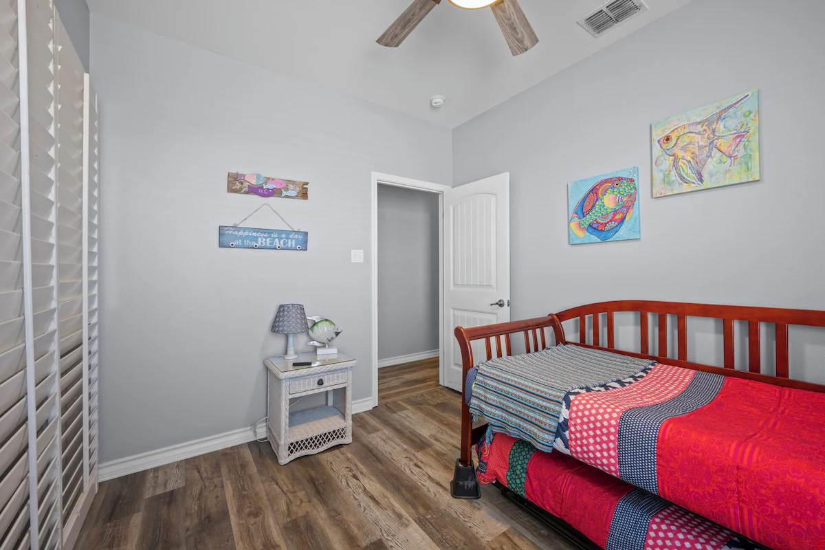 Relax in your coastal-themed bedroom with vaulted ceilings and cheerful artwork. The playful red daybed and warm wood floors create a bright, welcoming retreat after a day of adventure.