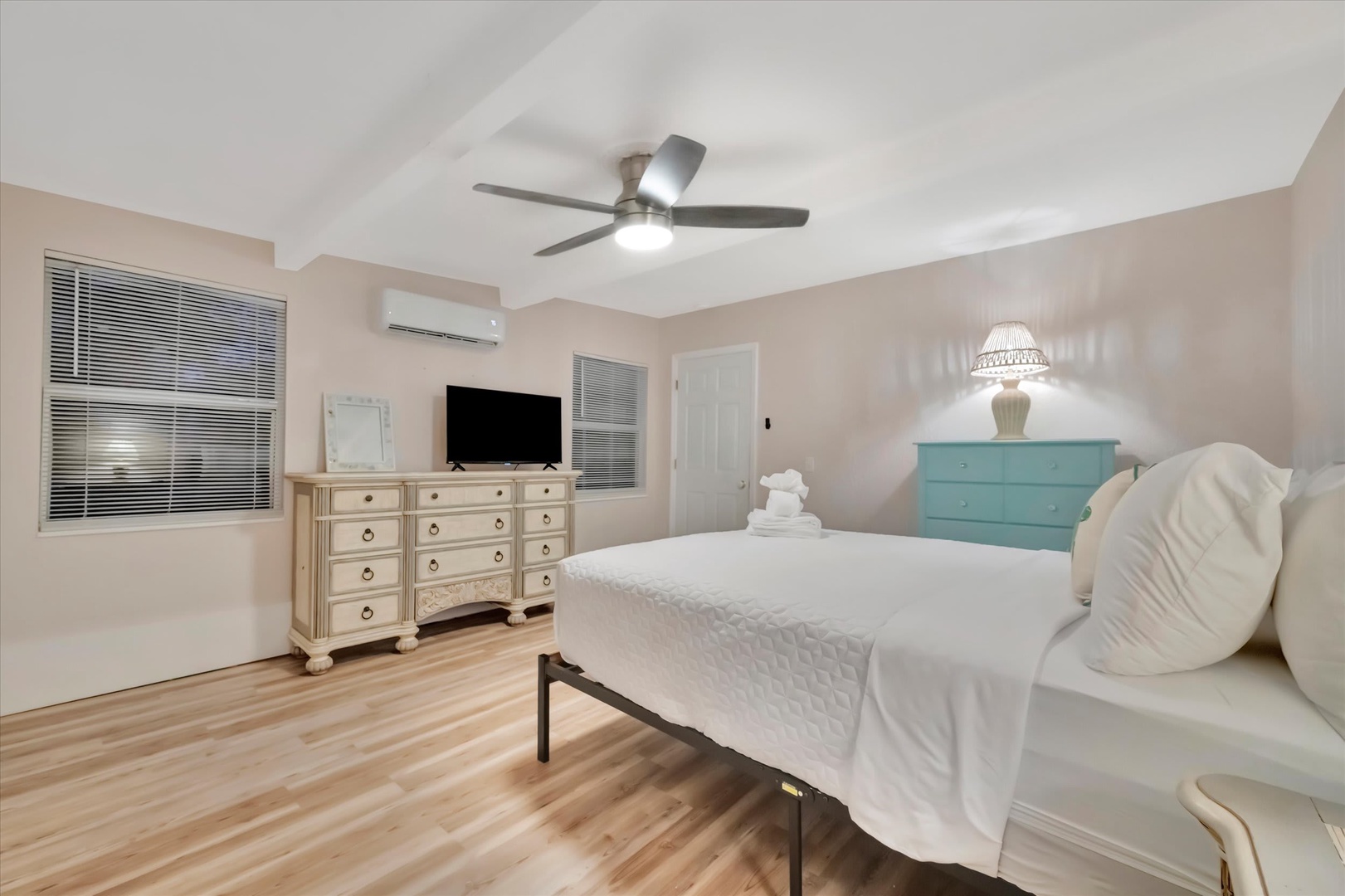 Slip into crisp white linens and enjoy the gentle breeze from the ceiling fan overhead. Your spacious bedroom invites restful nights with charming coastal touches and soft lighting to set the perfect mood.