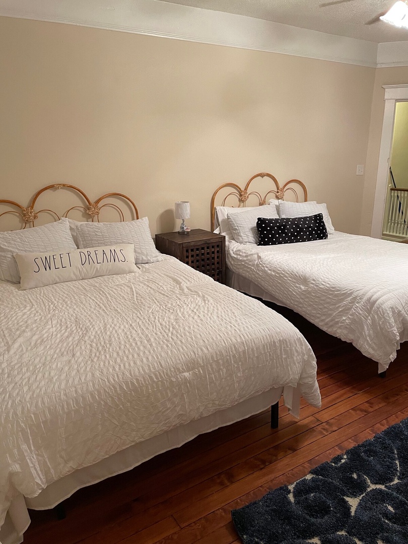 Sink into crisp white linens and charming rattan headboards after a day of exploring. This cozy room with warm wood floors offers flexible sleeping arrangements perfect for your group.