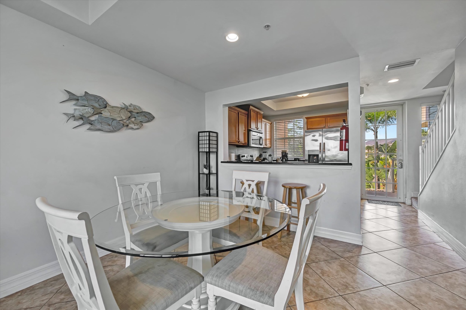 Gather around the glass dining table and enjoy meals with views of your fully-equipped kitchen and bright tropical greenery just beyond the door.
