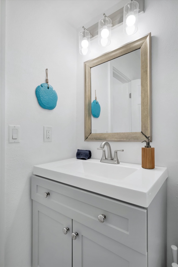 Step into your refreshed bathroom, where bright overhead lighting and coastal-inspired accents create a clean, calming space for your morning routine.