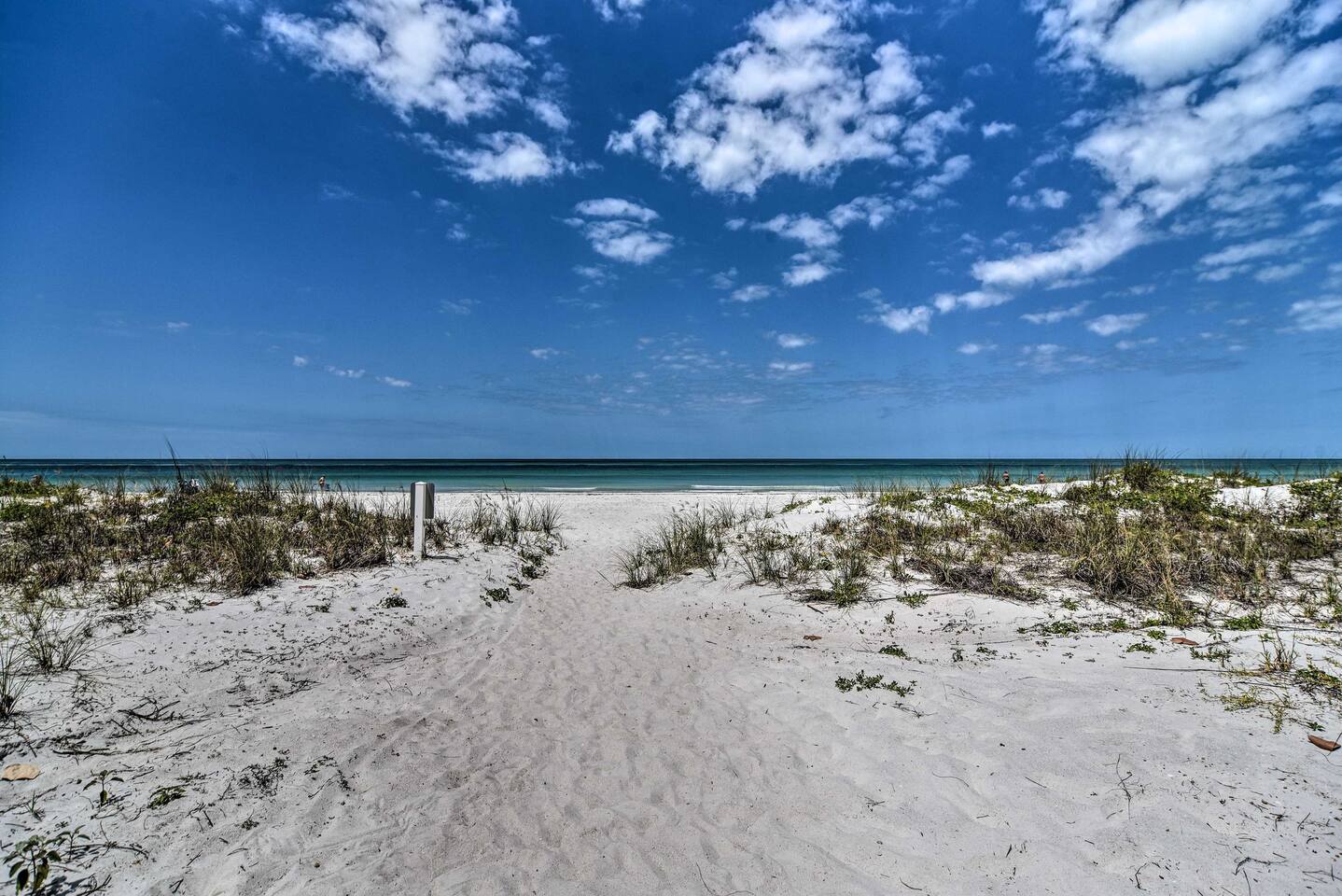 This pristine white sand beach and turquoise waters stretch out before the property, inviting peaceful strolls and endless ocean views under brilliant blue skies.