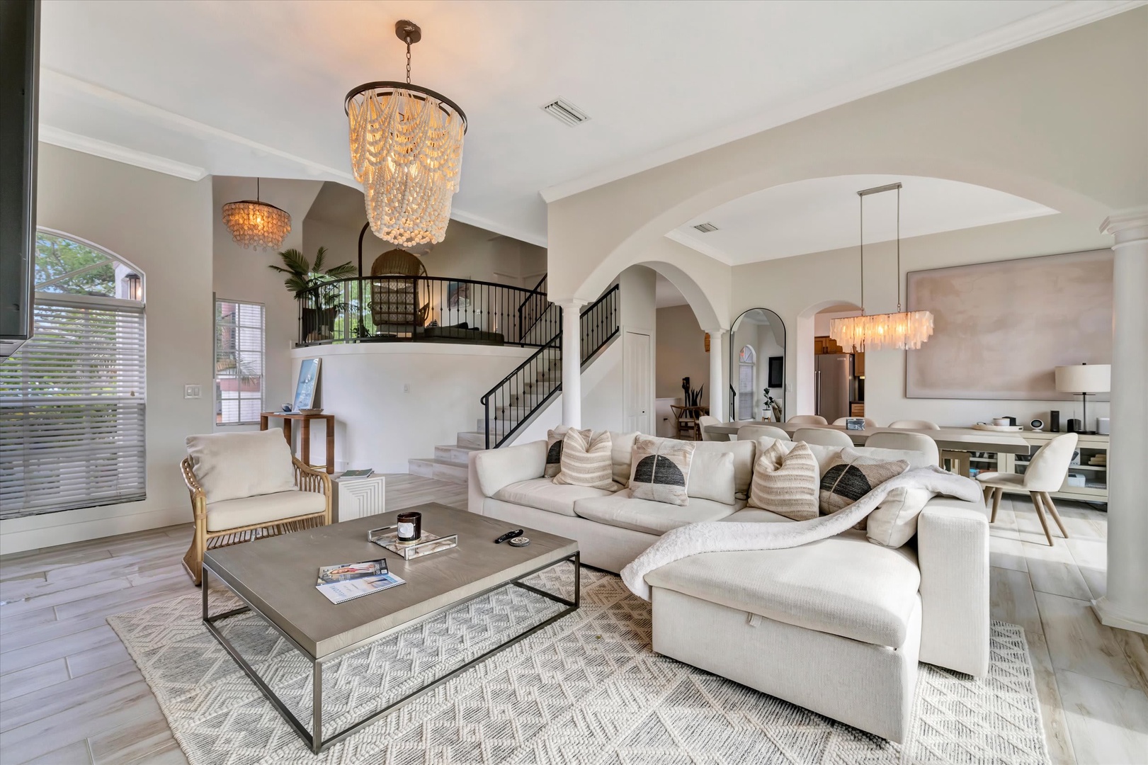 Sink into plush seating beneath a stunning chandelier in this bright, open living area with soaring ceilings and elegant archways designed for your relaxation and comfort.