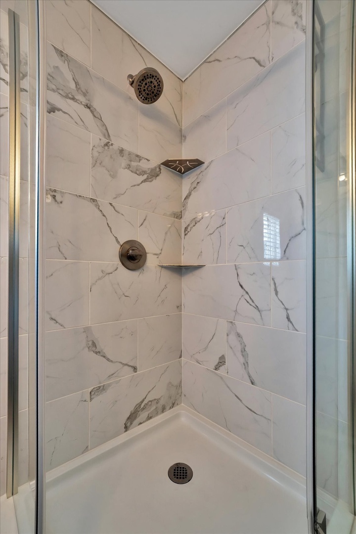Step into your private marble-look shower with rainfall head and convenient built-in niche—a sleek, refreshing retreat after a day of exploring.