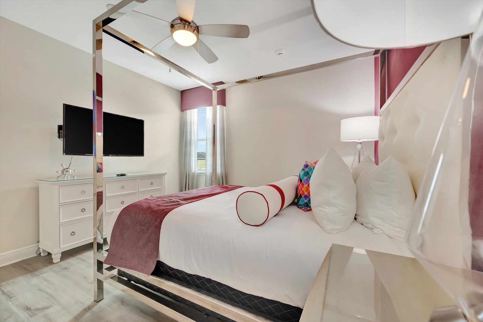 Drift off in this serene bedroom, where crisp white linens meet plush accents and soft rose tones. A ceiling fan keeps you cool while twin TVs and modern furnishings make you feel right at home.