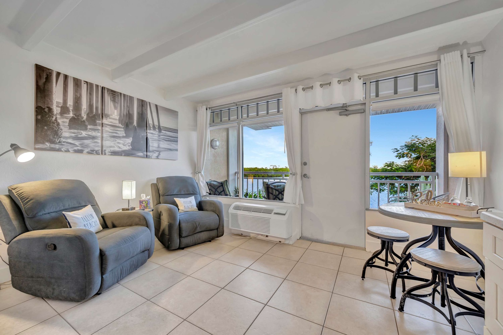 Settle into your cozy living space where plush recliners invite you to unwind while gazing at the tranquil waterfront just beyond your private balcony.