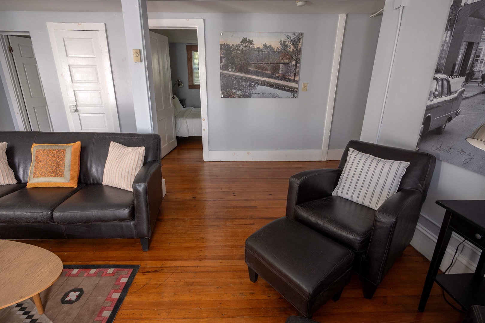 Unwind in your cozy living room with plush leather seating and warm hardwood floors. Step through to discover comfortable bedrooms just beyond the doorway.