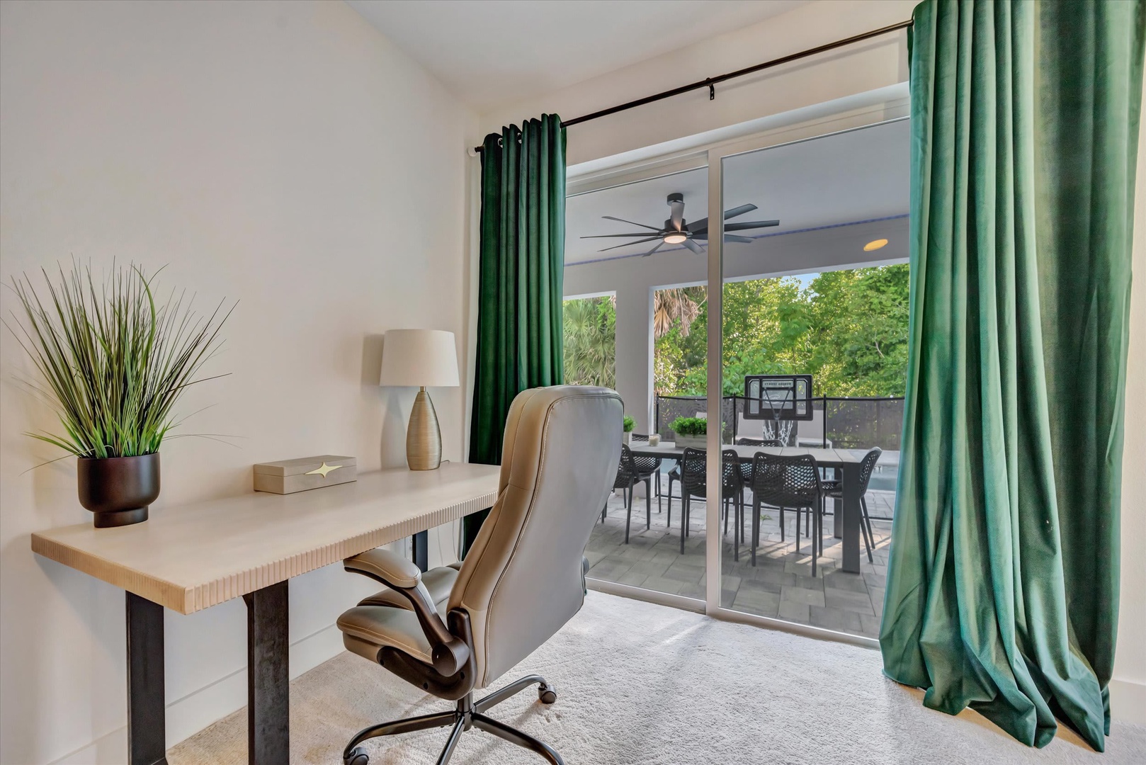 Step into your private workspace with lush green curtains framing a tranquil garden view. The covered patio just beyond your door invites you to take breaks surrounded by tropical greenery.