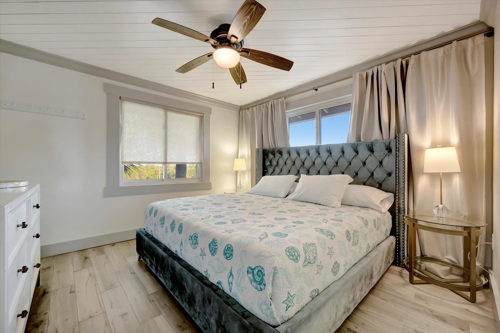 Slip into comfort in your serene bedroom, where coastal breezes from the ceiling fan and natural light set the tone for restful nights and peaceful mornings.