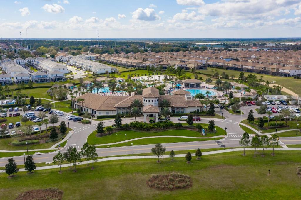 Aerial view of the resort community showcasing the main clubhouse, pool complex with waterpark amenities, surrounding neighborhoods, and natural lake visible on the horizon.