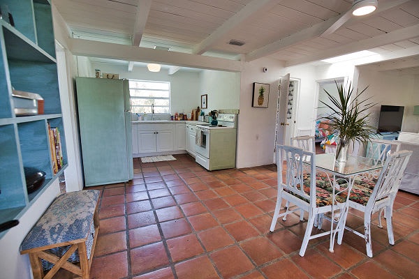 Step into your cheerful open-plan kitchen and dining area, where warm terracotta tiles and vintage-inspired appliances create a homey, coastal vibe—perfect for preparing fresh meals and gathering around the table.