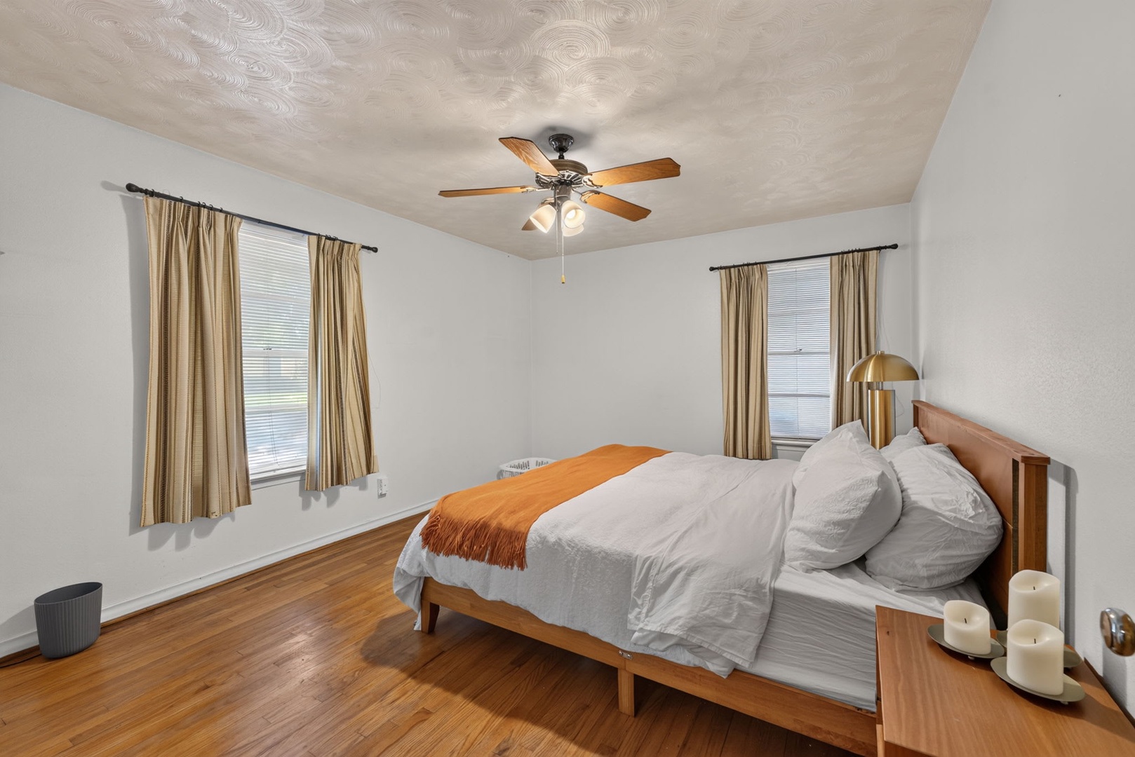 Step into your serene retreat where warm hardwood floors meet soft lighting and a plush bed draped in crisp linens. The ceiling fan keeps you cool while gentle natural light filters through, creating the perfect spot to unwind.