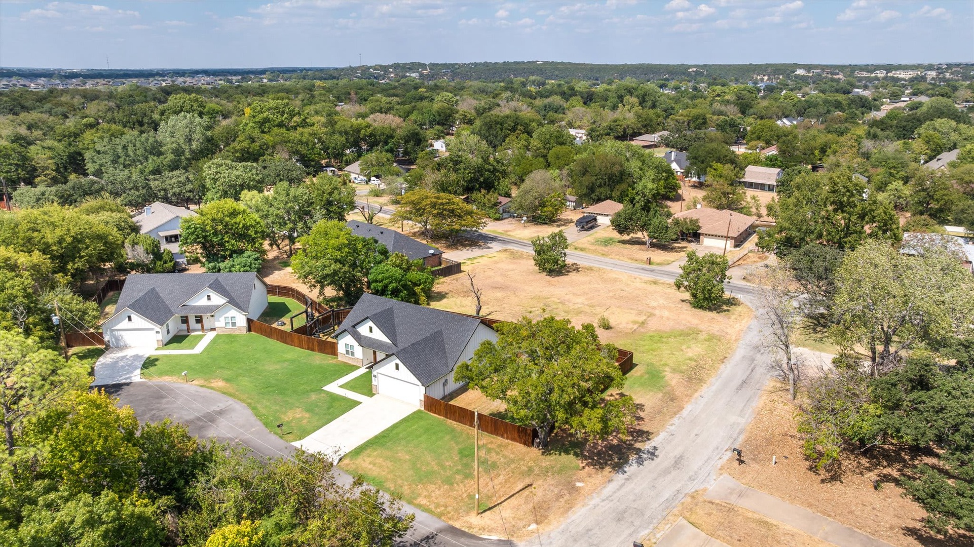 Aerial view of the property nestled in a quiet, tree-lined residential neighborhood with spacious green yards and easy street access.