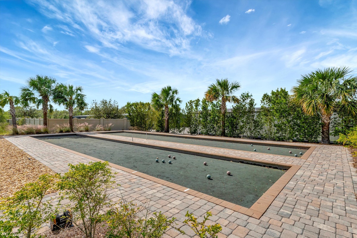 Full-size bocce ball court with smooth playing surface, tropical palm landscaping, and paver surround for hours of leisurely outdoor competition.