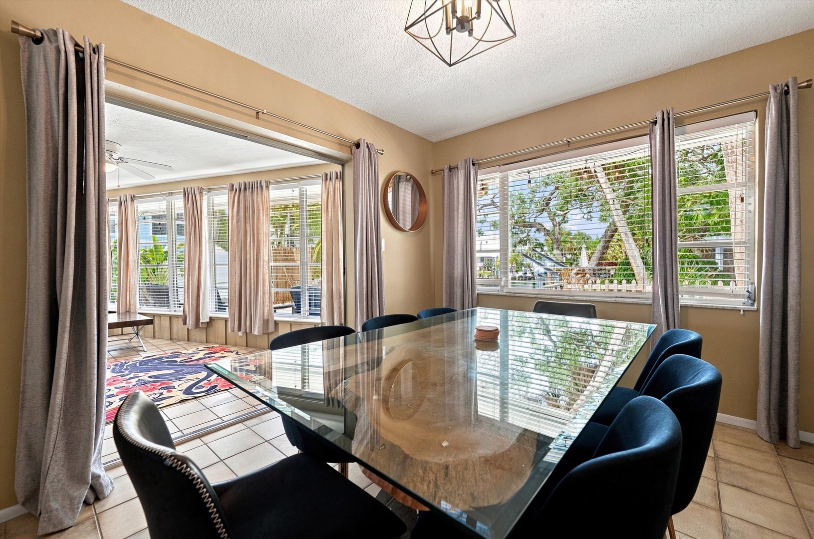 Natural light floods this inviting dining area, where your group can gather around the elegant glass table for meals and conversation, with views of the lush greenery just outside.