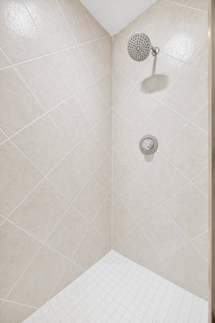 Step into your pristine walk-in shower with its soft beige tilework and rainfall showerhead—perfect for rinsing off after a day exploring.