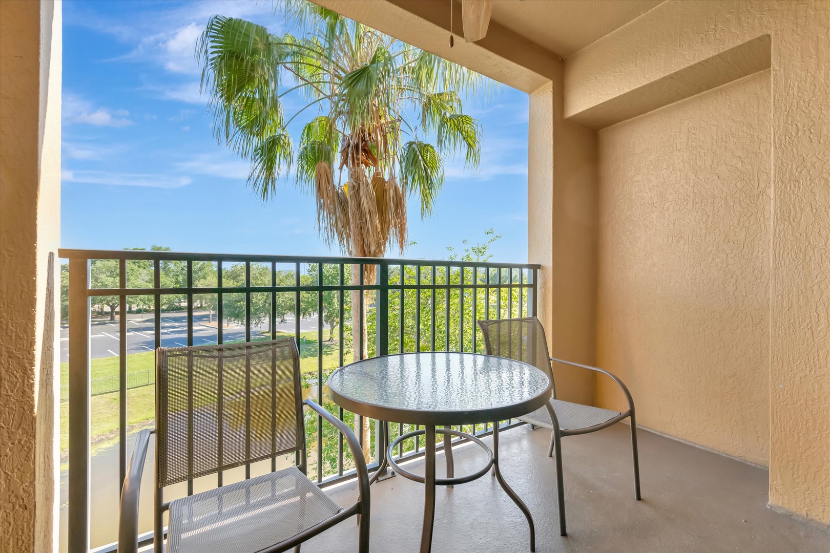 Your private balcony invites you to savor morning coffee or evening relaxation with a peaceful garden view and a swaying palm tree just beyond the railing.