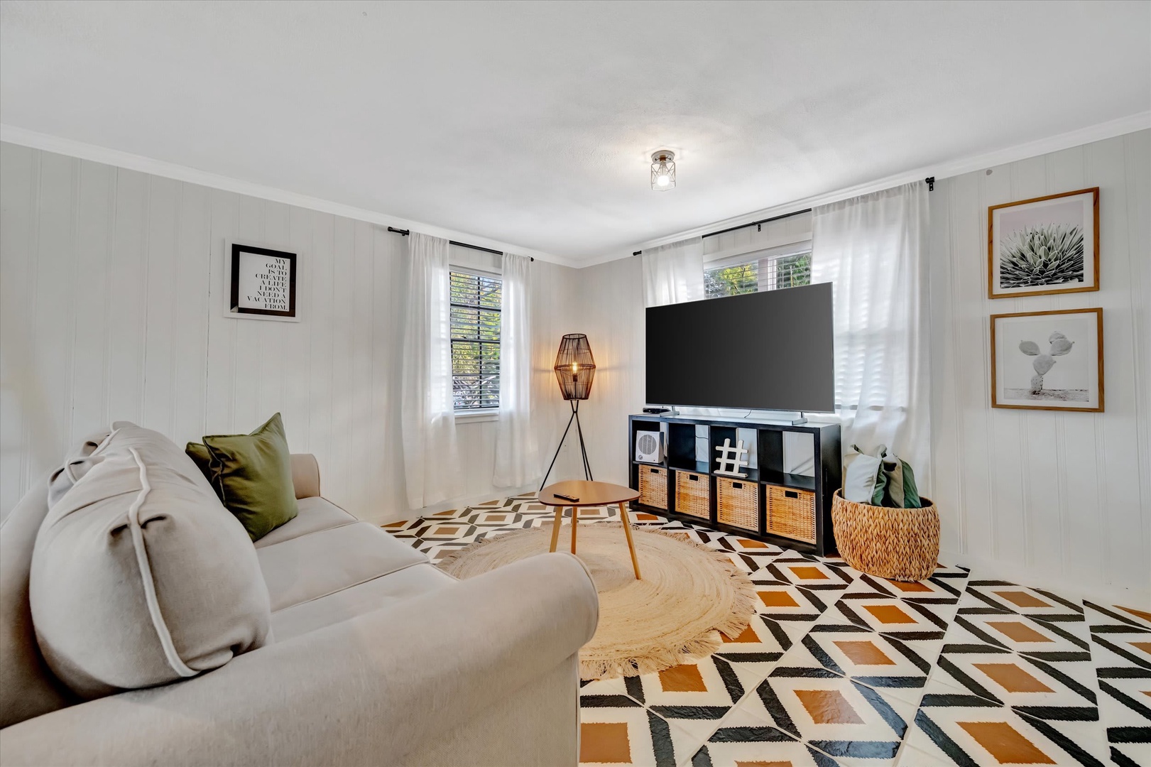 Curl up on the plush sofa and enjoy movie nights in your private living room, where modern comfort meets charming cottage-style walls and natural light pours through white curtains.