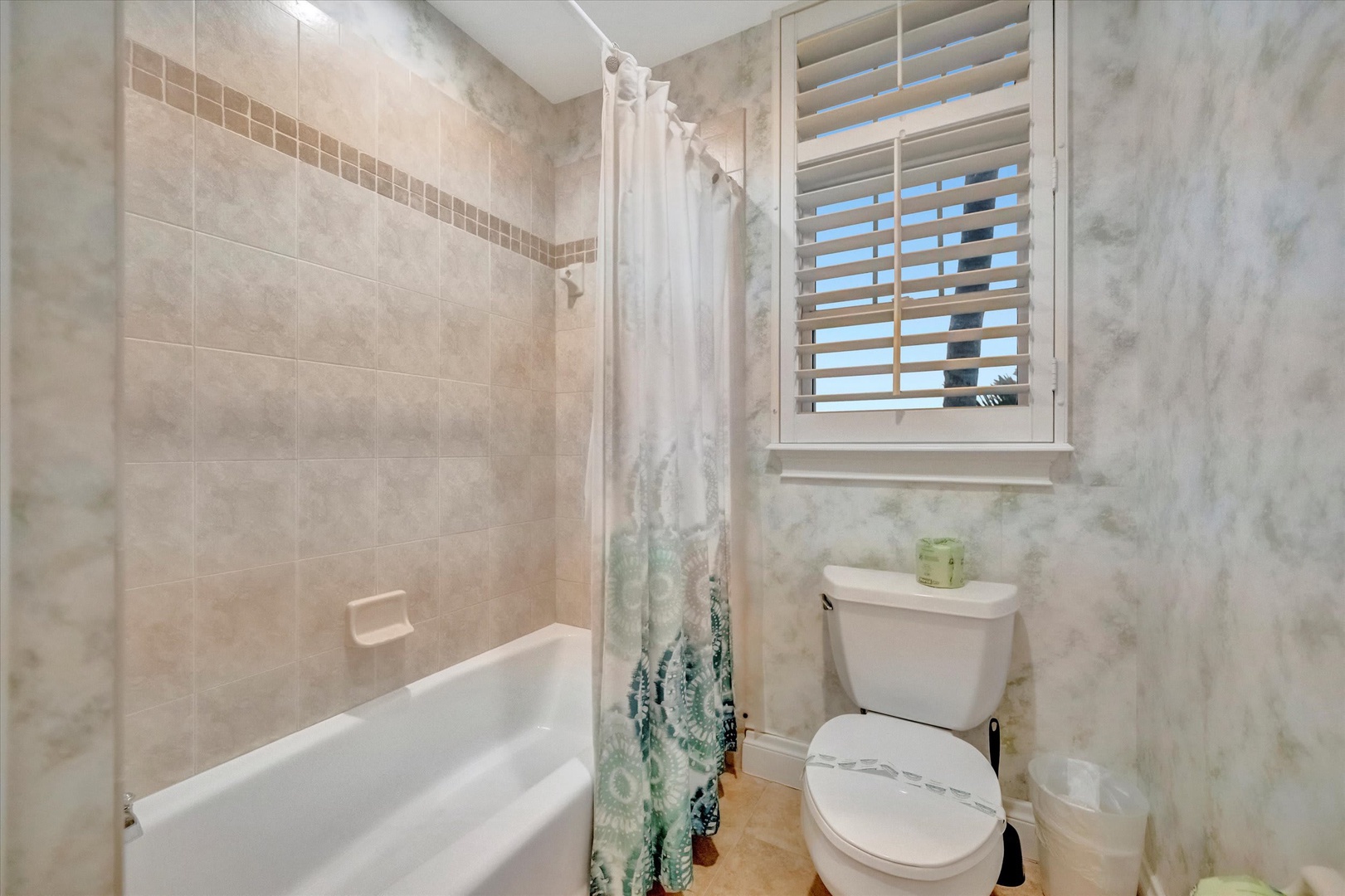 Refresh after your adventures in this clean, well-lit bathroom with a full tub-shower combo, modern tiling, and natural light from the window.