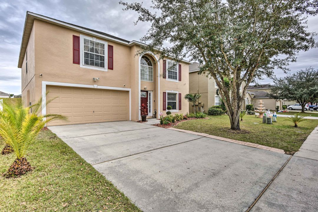 A two-story home features a welcoming arched entryway, red shutters, and a two-car garage. The property sits on a landscaped corner lot in a quiet residential neighborhood.