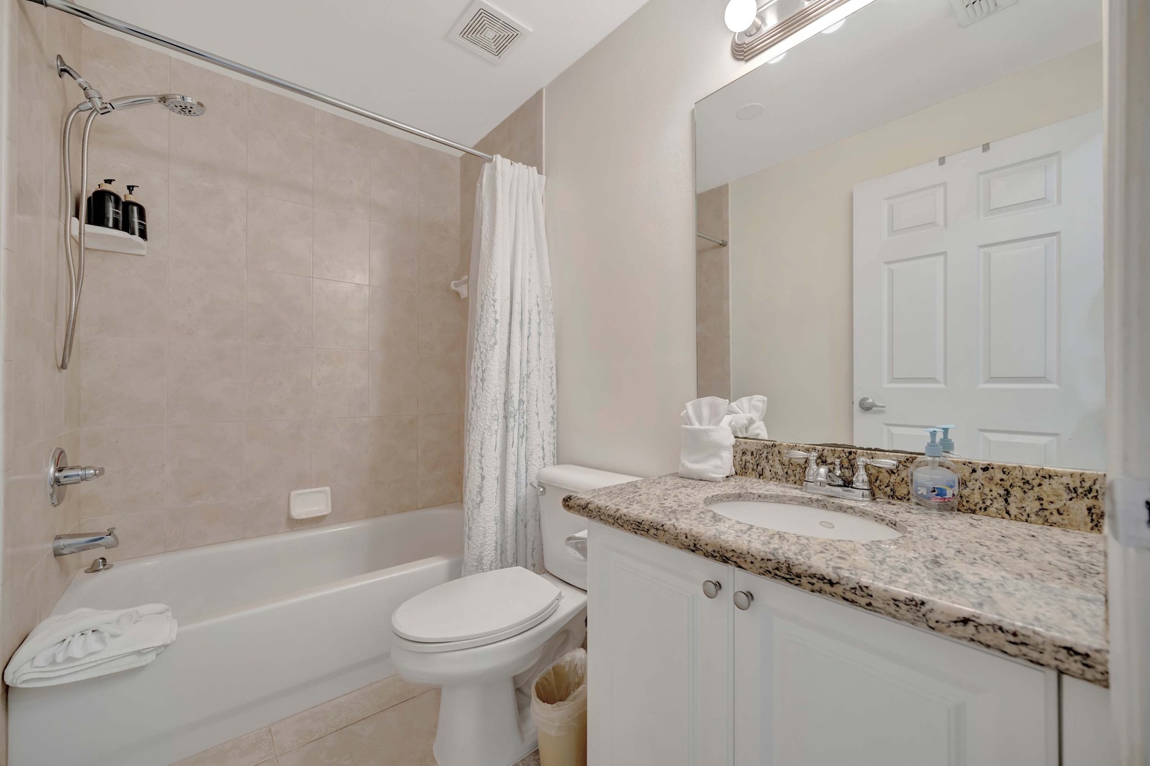 Your private bathroom offers a soothing neutral palette with a shower-tub combo, fresh towels, and plenty of counter space to make you feel right at home.