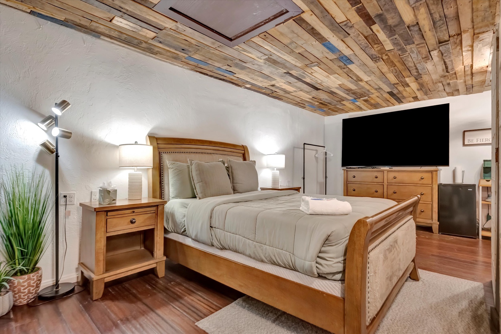 Drift off under a striking reclaimed wood ceiling—your restful retreat features a plush bed, warm wood tones, and thoughtful touches like bedside lighting and a mini-fridge for your convenience.