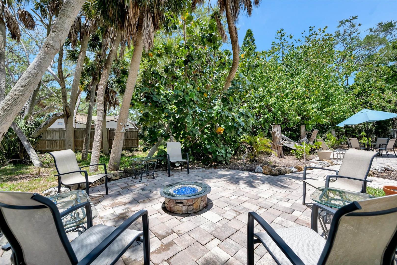 Gather around the fire pit in this peaceful backyard oasis, surrounded by lush tropical palms and greenery. Your private outdoor escape features plenty of seating for evening conversations under the Florida sky.