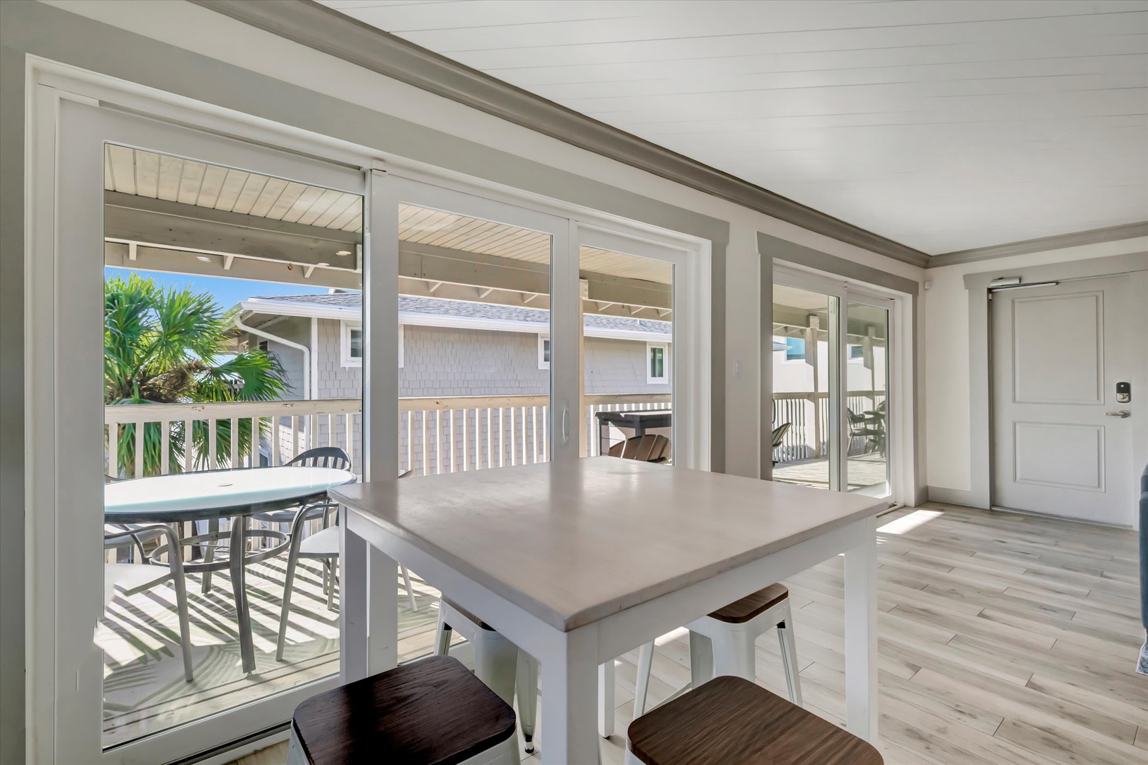 Step into your bright, open kitchen and dining area where large glass doors frame views of swaying palms and your private deck. Gather around the table for coffee or meals with natural light pouring in from every angle.