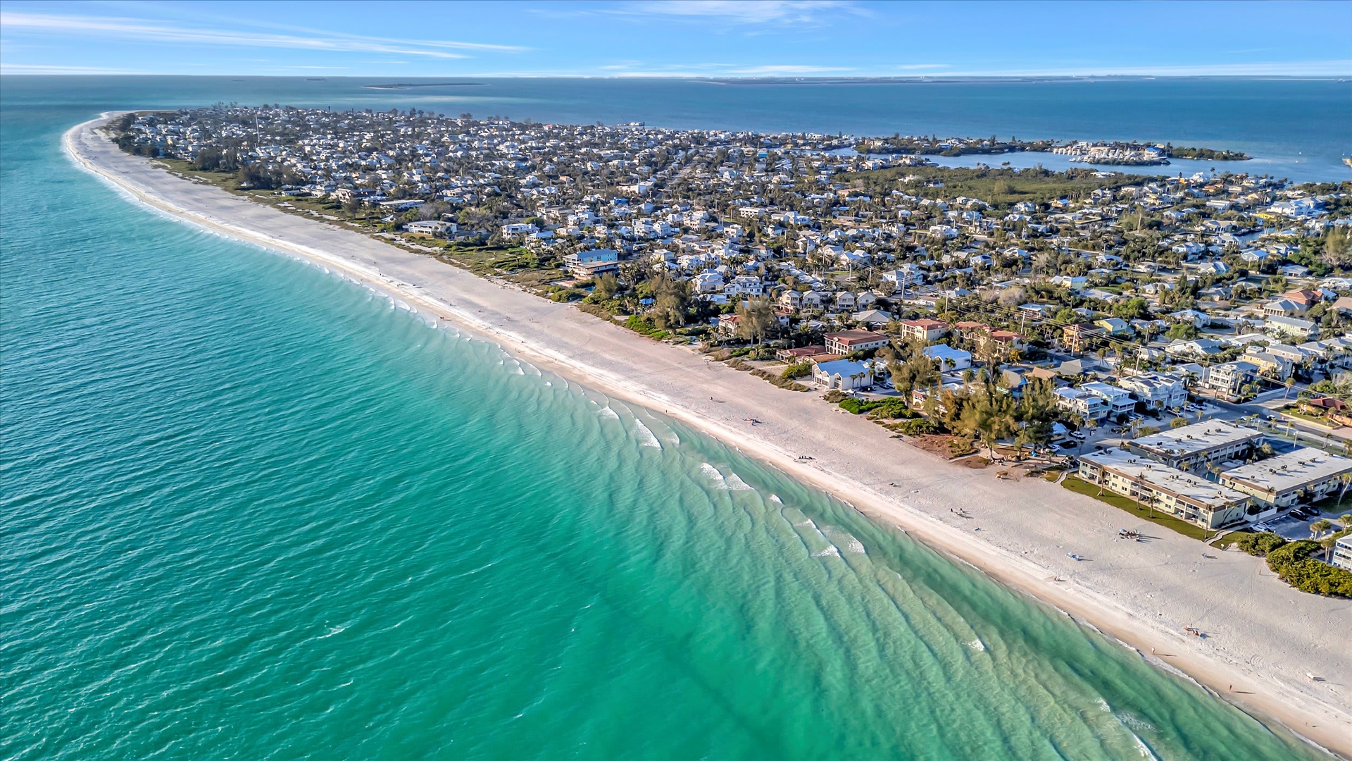 Aerial view of a pristine coastal community along turquoise waters and white sandy beaches, showcasing the beautiful surrounding area.