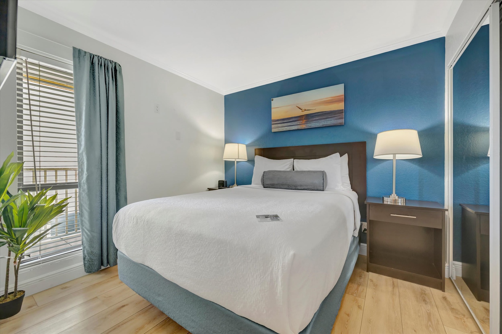 Unwind in your serene bedroom retreat, where crisp white linens meet soothing coastal-blue tones. Natural light filters through while matching lamps offer a warm evening glow.