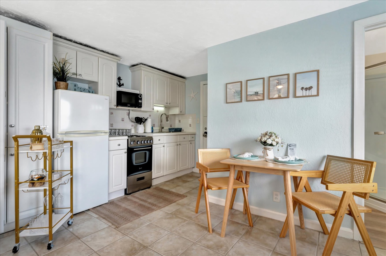 Step into your coastal-inspired kitchen and dining area, where soft blue walls and beachy touches create a serene retreat. Enjoy your morning coffee at the cozy table for two before preparing fresh meals in your fully equipped space.