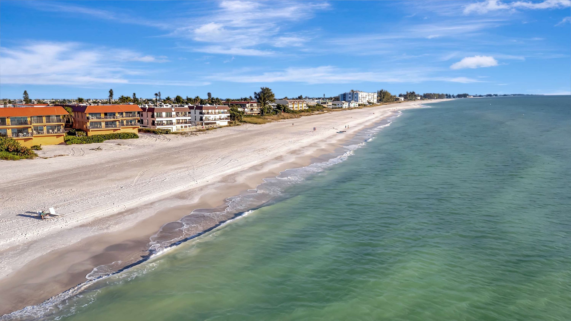 Aerial view of the beachfront property and surrounding coastal neighborhood, with the serene shoreline just steps away.