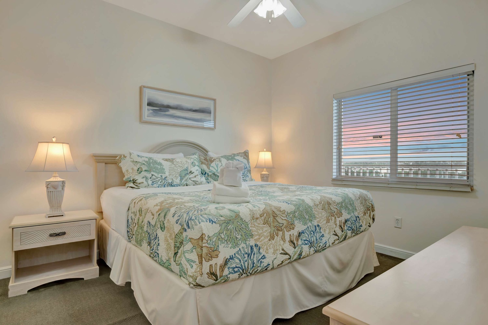 Drift off to sleep under coastal-themed bedding while a glimpse of dusk colors the sky beyond your window. The soft lighting and peaceful decor create your perfect seaside retreat.