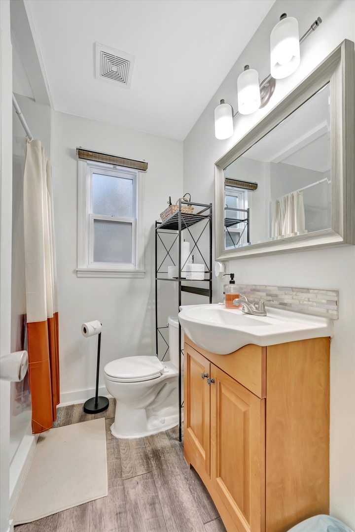 Freshen up in your bright, modern bathroom with warm wood cabinetry, gleaming fixtures, and plenty of natural light to start your day right.