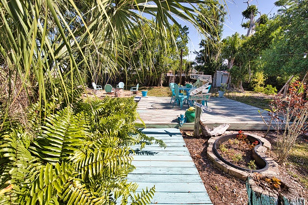 Your own tropical oasis awaits, complete with colorful Adirondack chairs nestled beneath swaying palms and a fire pit ready for starlit evenings. Stroll the charming walkways and soak in the lush, island-inspired vibe.