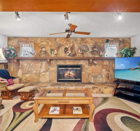 Cozy up by the stone fireplace in your inviting living room, where warm wood tones and comfortable seating create the perfect retreat after a day of adventure.