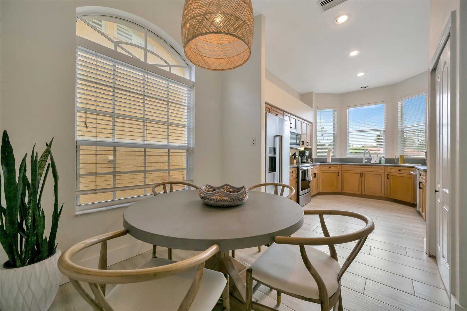 Gather around your private dining table beneath a warm woven pendant, where bright windows and an open kitchen create the perfect setting for memorable morning coffee and leisurely meals with loved ones.