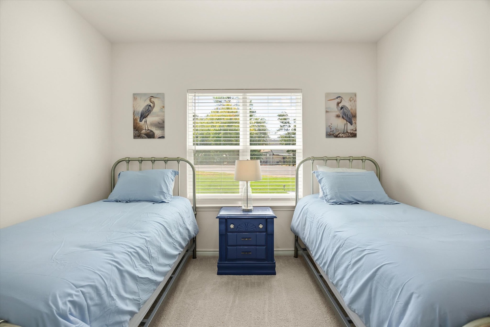 Rest easy in this peaceful twin bedroom with crisp linens and coastal accents. Soft morning light filters through the window, creating a serene retreat perfect for your getaway.