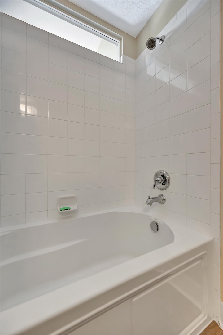 Sink into a long, relaxing soak in this pristine bathtub. Clean white tile surrounds you, while natural light from above creates a bright, refreshing space for unwinding after exploring.