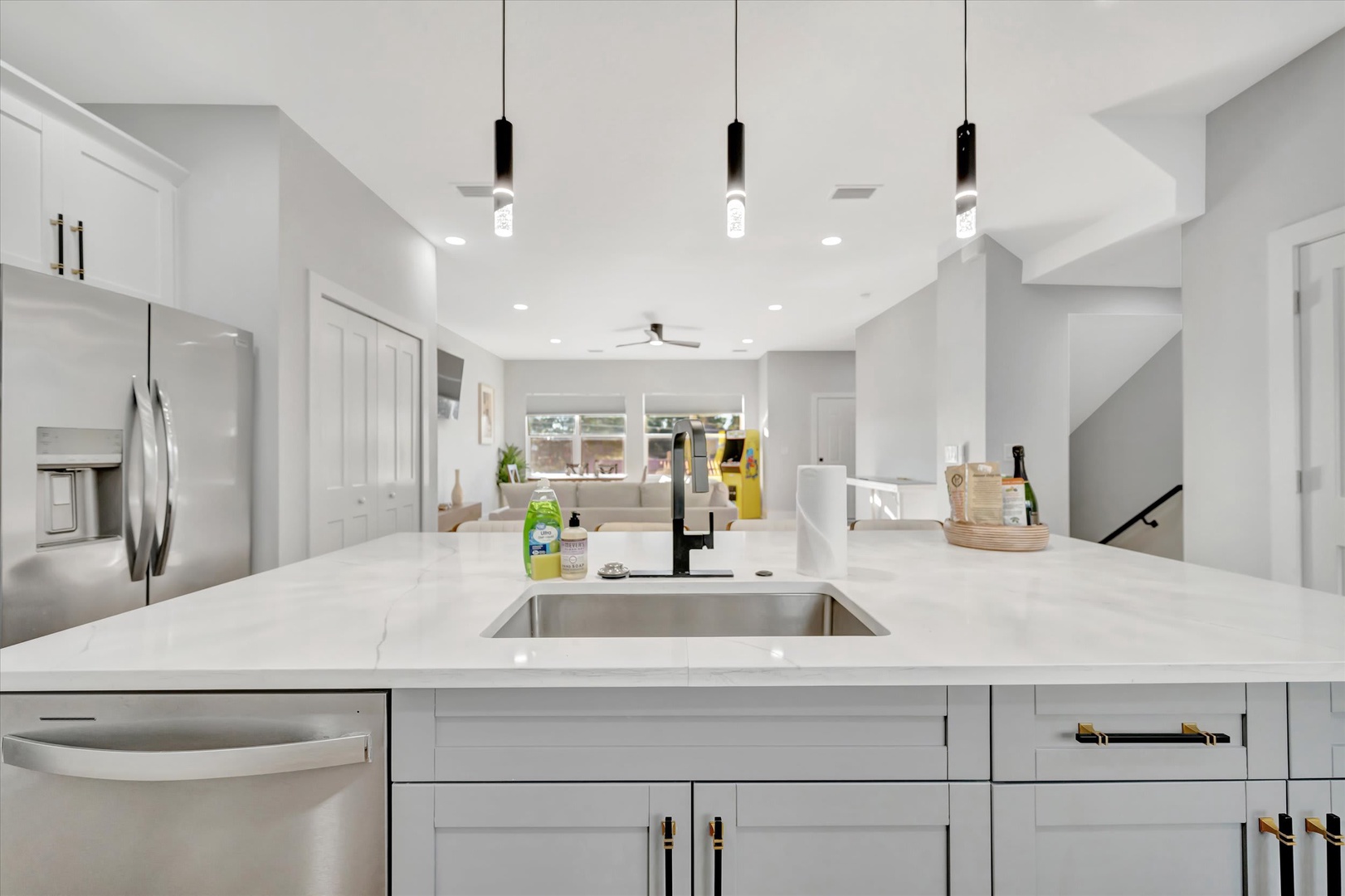 This sleek, modern kitchen welcomes you with gleaming white countertops, premium stainless appliances, and bright open-concept design flowing seamlessly into the living areas. You'll love the clean lines and contemporary lighting overhead.