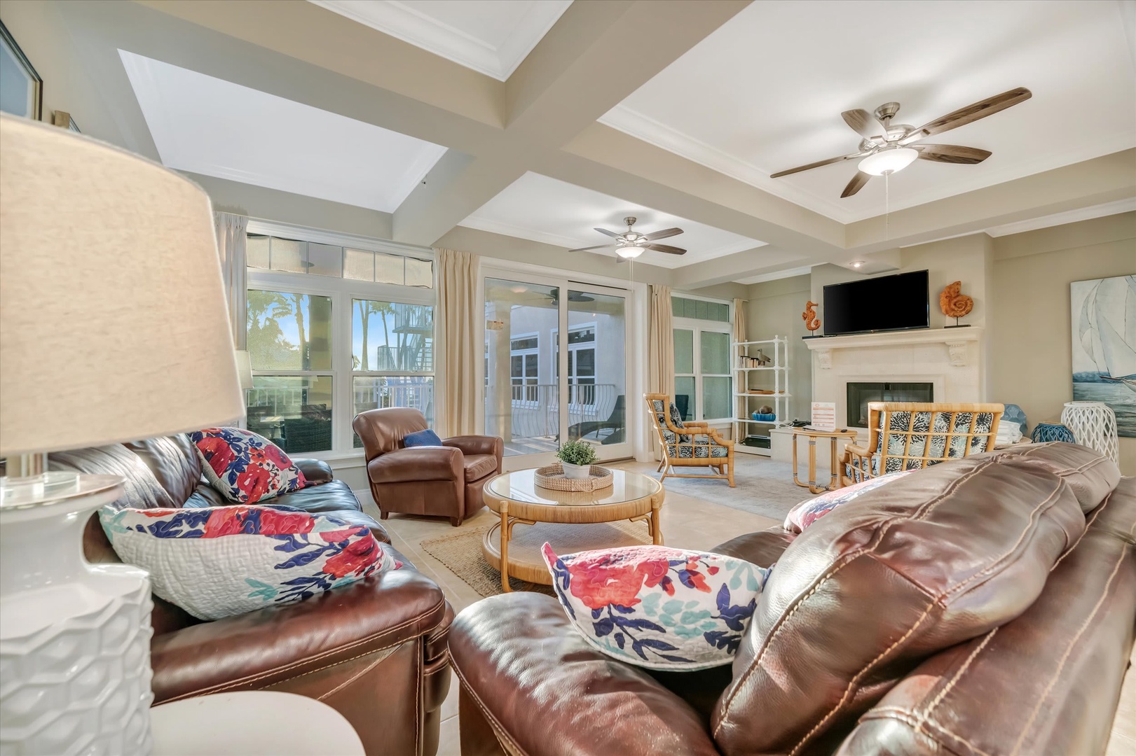 Sink into plush leather seating beneath vaulted ceilings and gentle ceiling fans. Your light-filled retreat opens to an outdoor patio through glass doors, blending indoor comfort with breezy tropical relaxation.