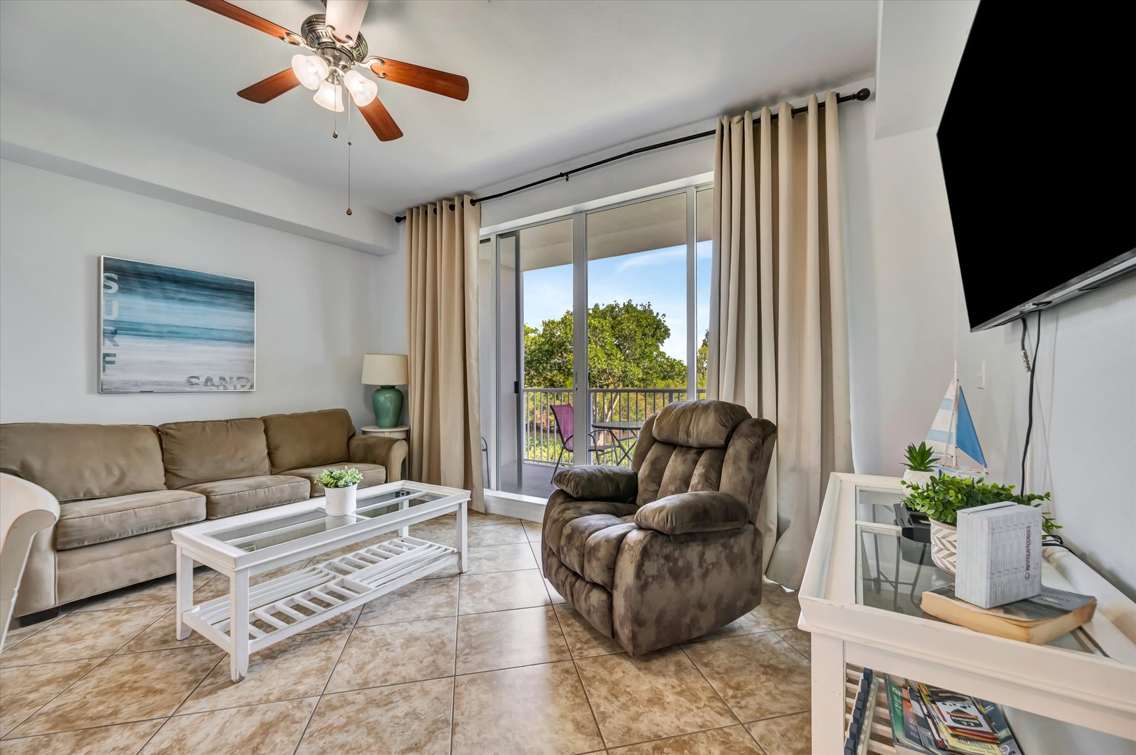 Sink into the plush sofa and let the ceiling fan keep you cool as you unwind in your inviting living space, with your private balcony and natural greenery just beyond the glass doors.