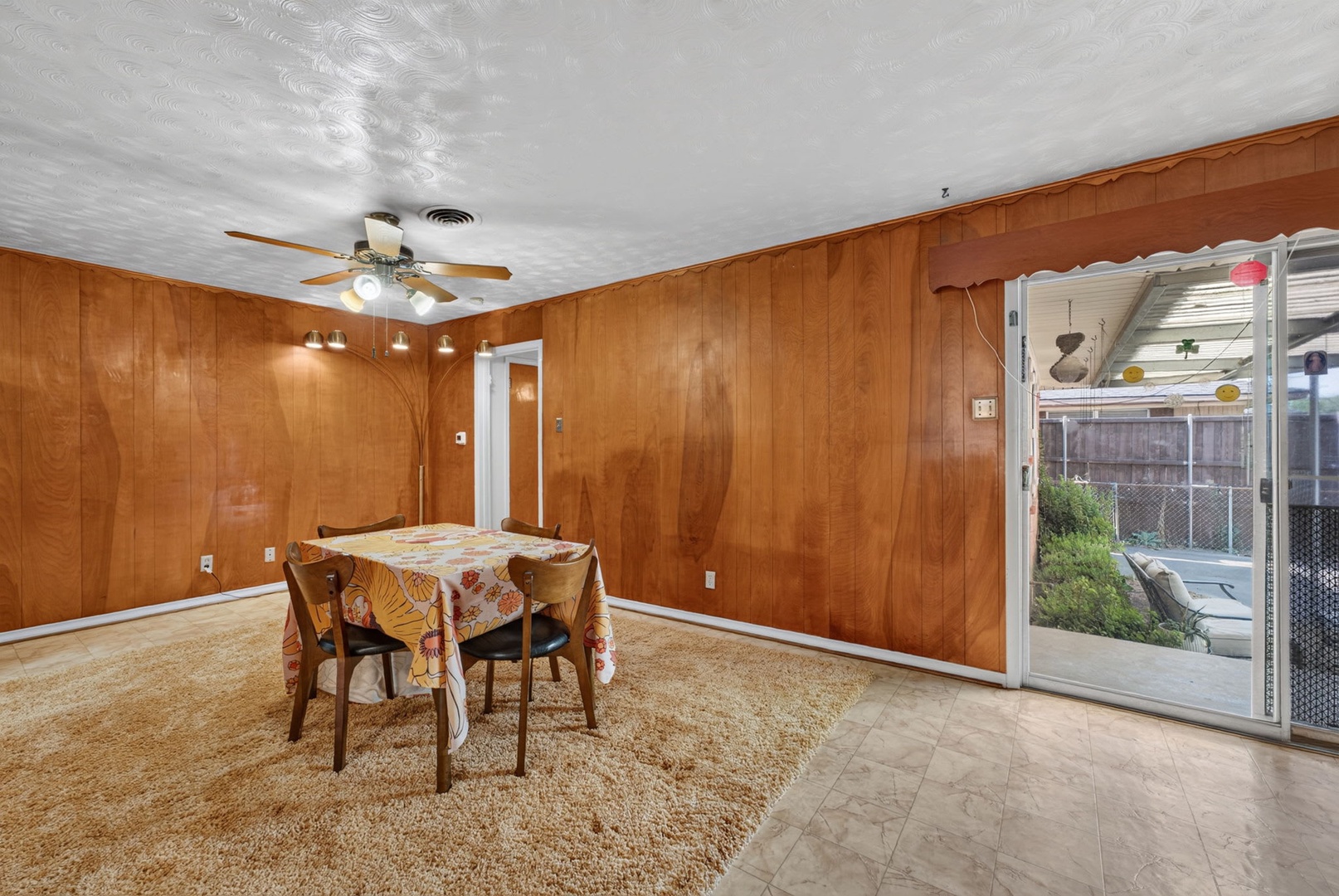 Gather around the table in your warm, wood-paneled dining room, where a ceiling fan keeps you comfortable and sliding glass doors open to your private patio and outdoor space.