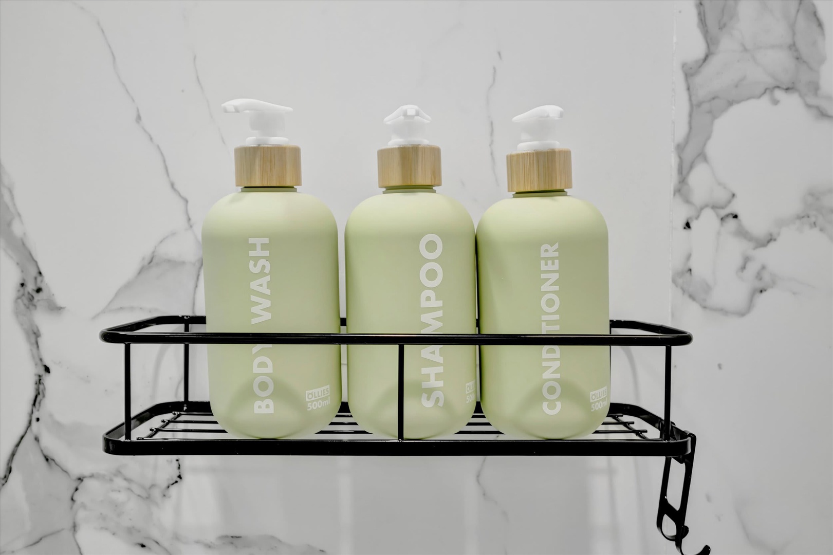 Thoughtfully selected bath amenities await your arrival, including body wash, shampoo, and conditioner displayed in a sleek wall caddy against elegant marble tile.
