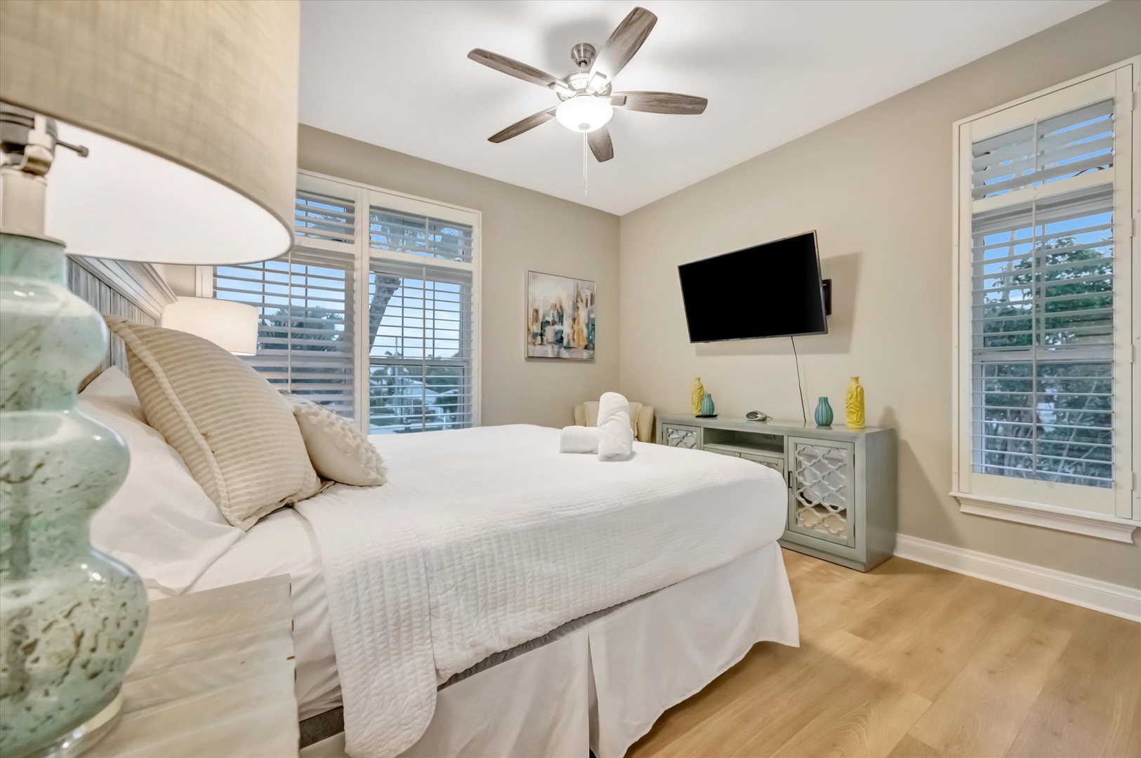 Relax in your bright, peaceful bedroom with crisp linens and a gentle ceiling fan. Large windows with plantation shutters let in natural light while keeping things private and comfortable.