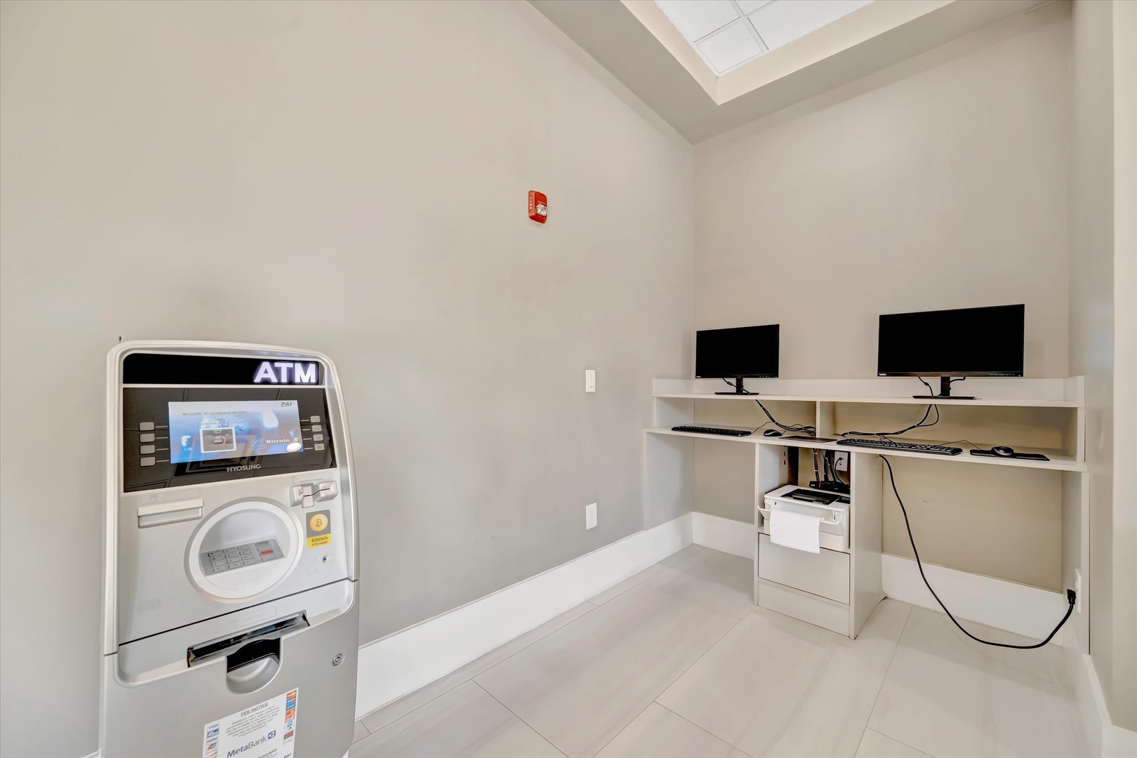 A business center providing convenient access to an ATM, dual computer workstations, and high ceilings with natural skylight above for comfortable productivity during your stay.