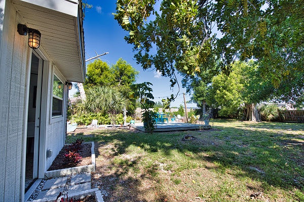 A private backyard awaits you with mature shade trees, open lawn space, and a glimpse of the sparkling pool area—perfect for relaxing or entertaining on sunny days.