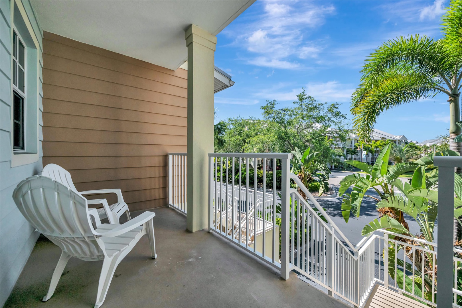 Step onto your private balcony and soak in the lush tropical surroundings. White chairs invite you to sip morning coffee or unwind as breezes carry the scent of palms and greenery.